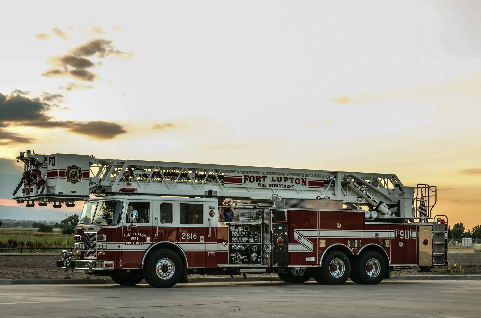 A fire truck with an extended ladder at sunset.