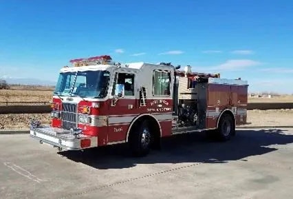 A fire truck parked on a concrete surface with clear skies in the background.