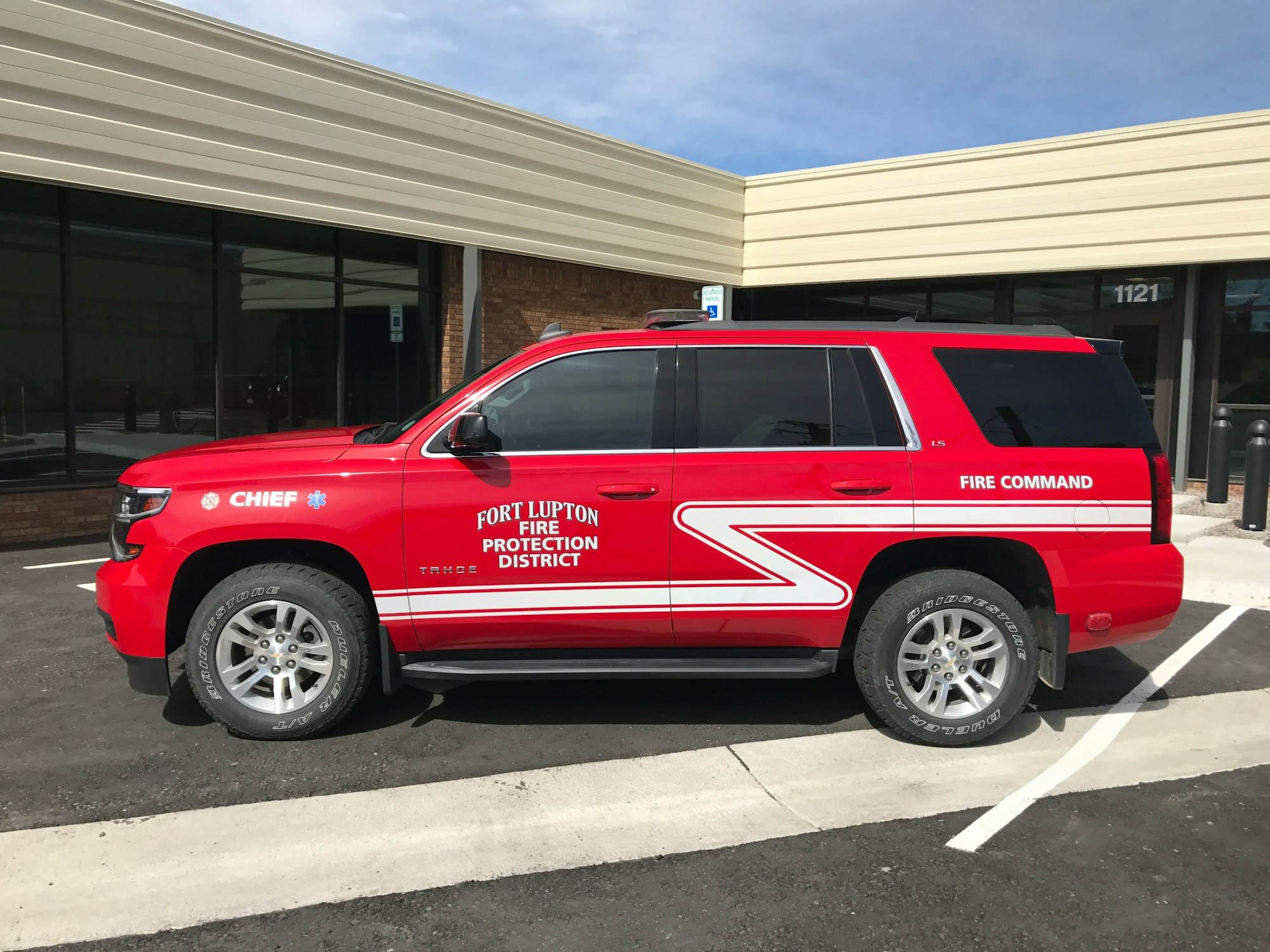 A red fire chief SUV with "Fire Command" text parked in front of a building.