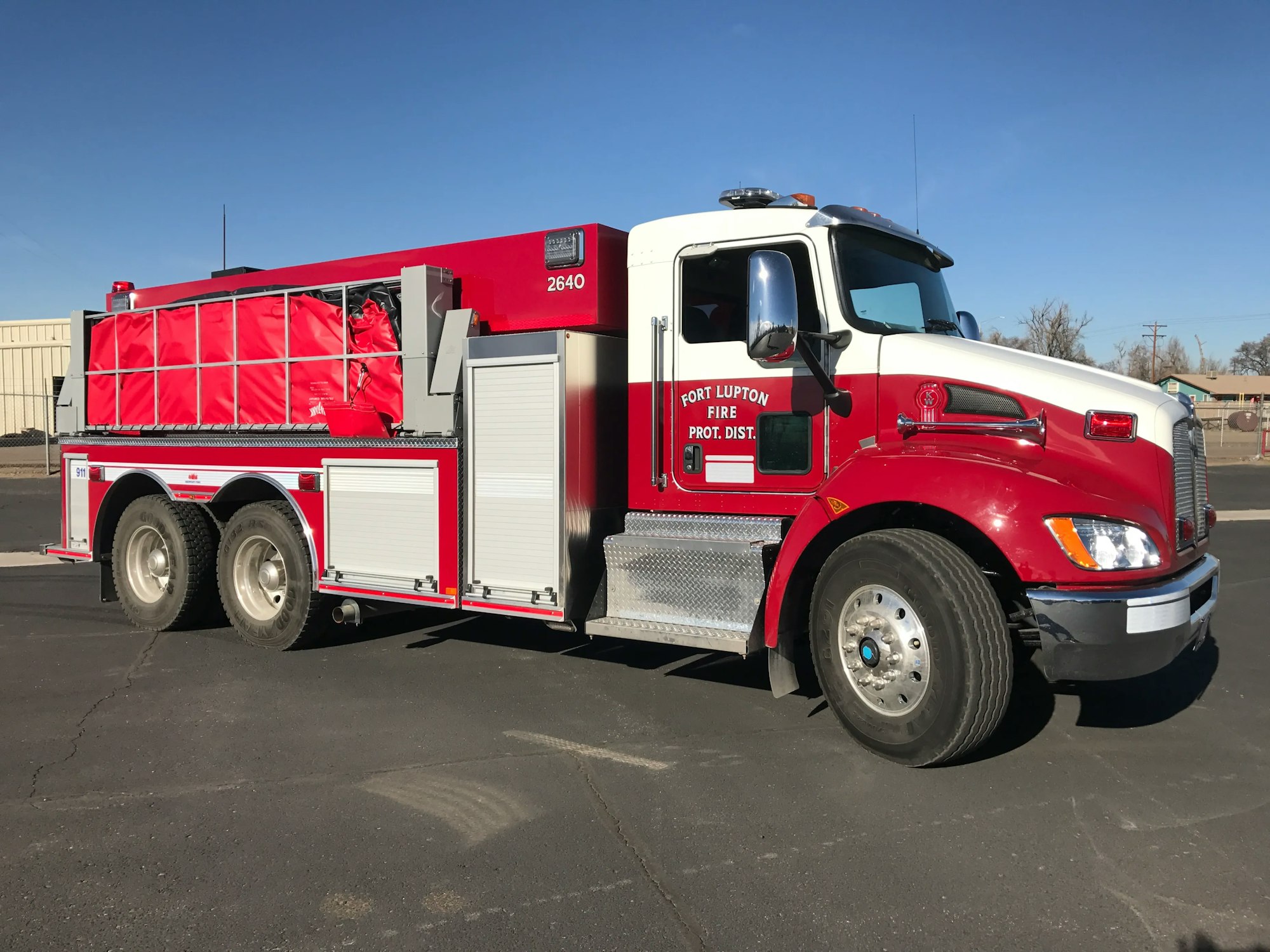 A red fire truck parked on an asphalt surface under a clear sky.