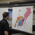 A person looking at a colorful, detailed map or chart mounted on a wall.