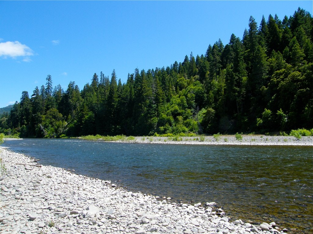 photo of the Eel River from the rocky shore across to the tree covered hills.