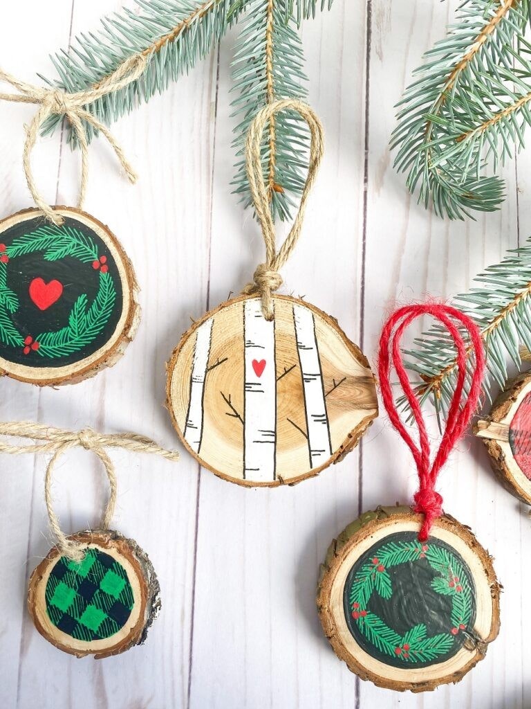 Hand-painted wooden Christmas ornaments with fir branch on white wood background.