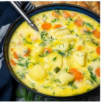 A bowl of vegetable soup with potatoes, carrots, and herbs.