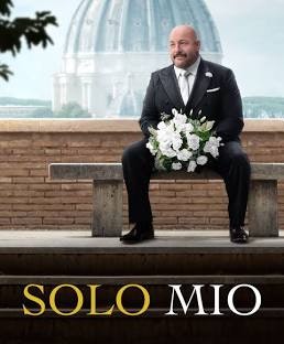 A man in a suit sits on a bench holding a bouquet, with a historic dome in the background. The text reads "SOLO MIO."