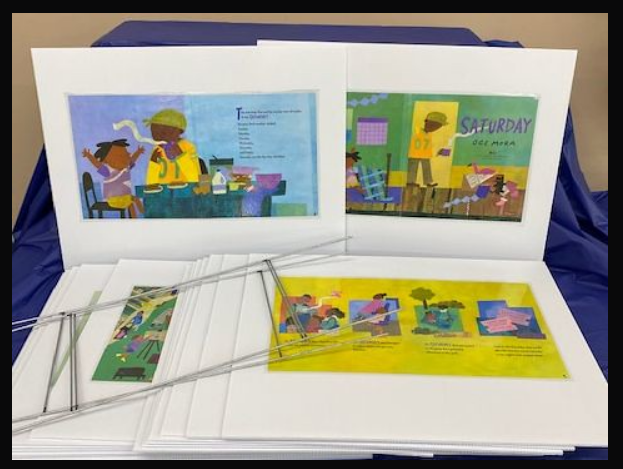 Illustrated posters on a table with colorful pictures and text, placed on a blue cloth.