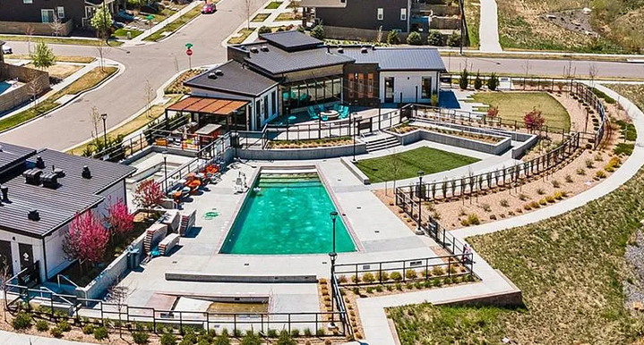 Aerial view of a modern building with a swimming pool, outdoor seating, landscaped areas, and pathways.
