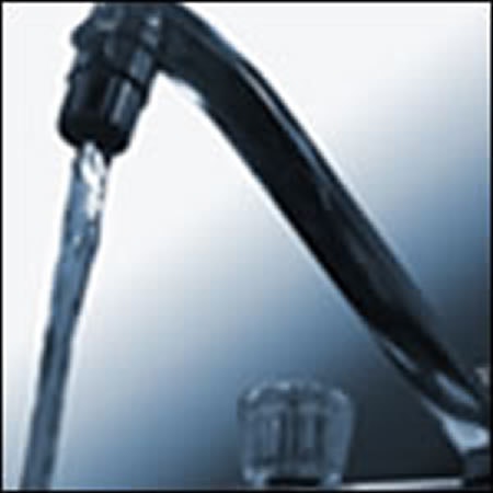 A faucet with running water against a blurred background.