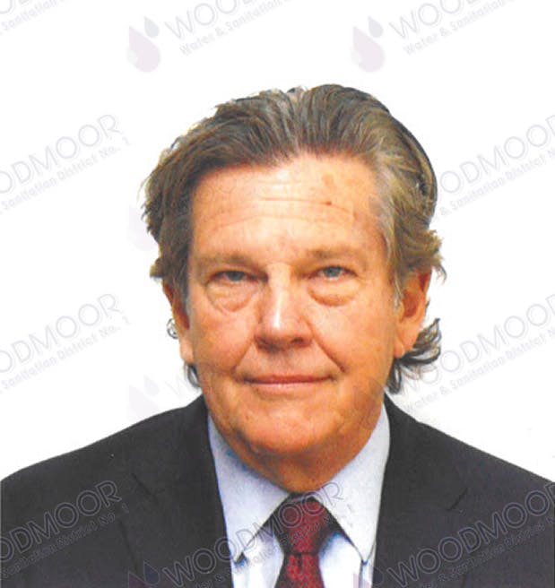 A person in a suit and tie with the watermark "WOODMOOR" in the background.