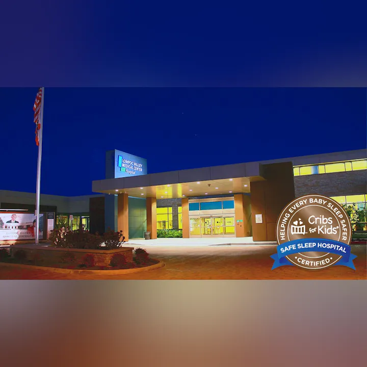 Image shows the entrance of Lompoc Valley Medical Center at night, featuring a sign and certification for safe sleep for infants.