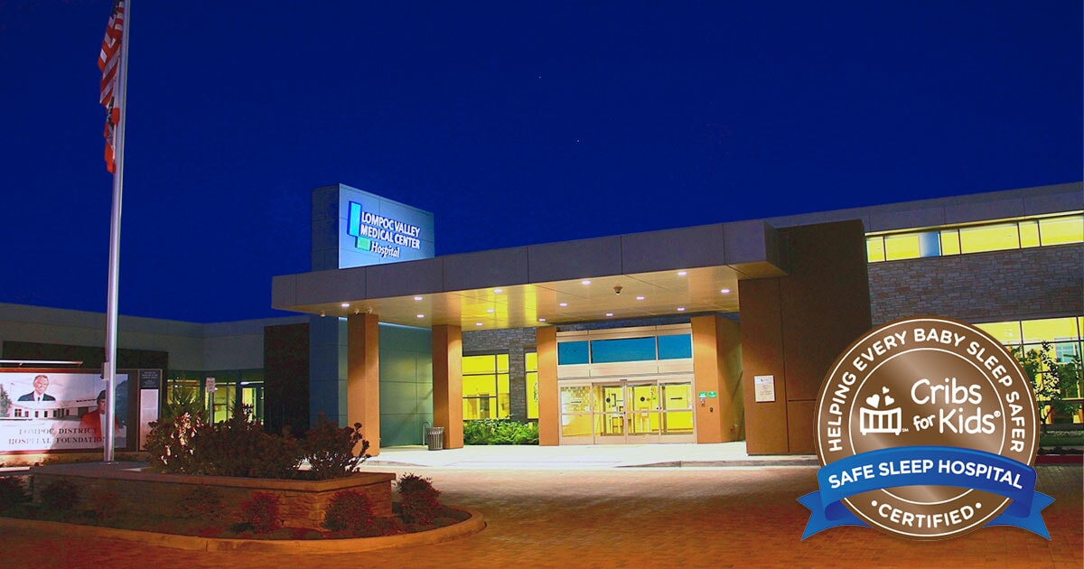 Image shows the entrance of Lompoc Valley Medical Center at night, featuring a sign and certification for safe sleep for infants.
