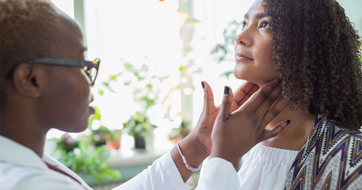 A person examines another's neck, possibly in a health or beauty context, with plants visible in the background.