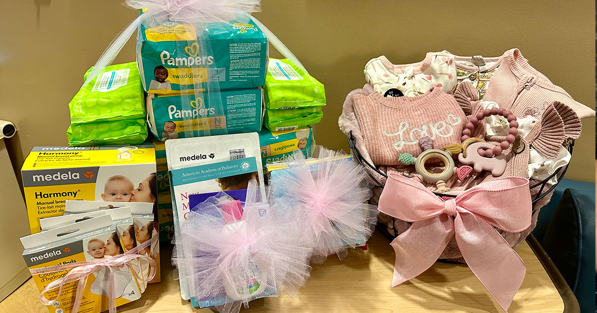 The image shows baby supplies, including diapers, clothing, and nursing products, arranged in gift baskets.