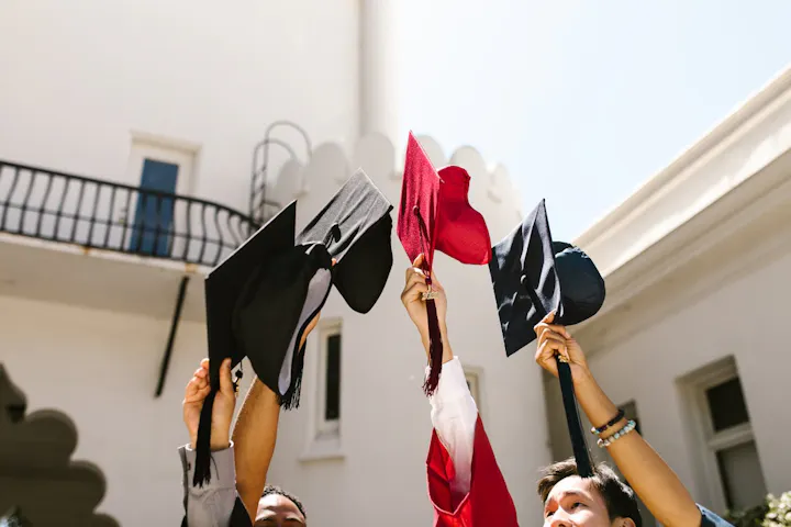 A group of graduates celebrating by throwing their caps in the air, showcasing joy and accomplishment.