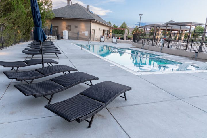 Swimming pool with lounge chairs, a building, and a covered seating area.