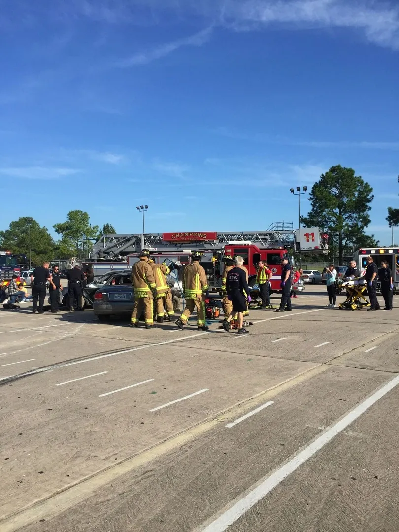 Emergency responders at a scene, with firefighters, a fire truck, and a vehicle, likely attending to an accident or drill.