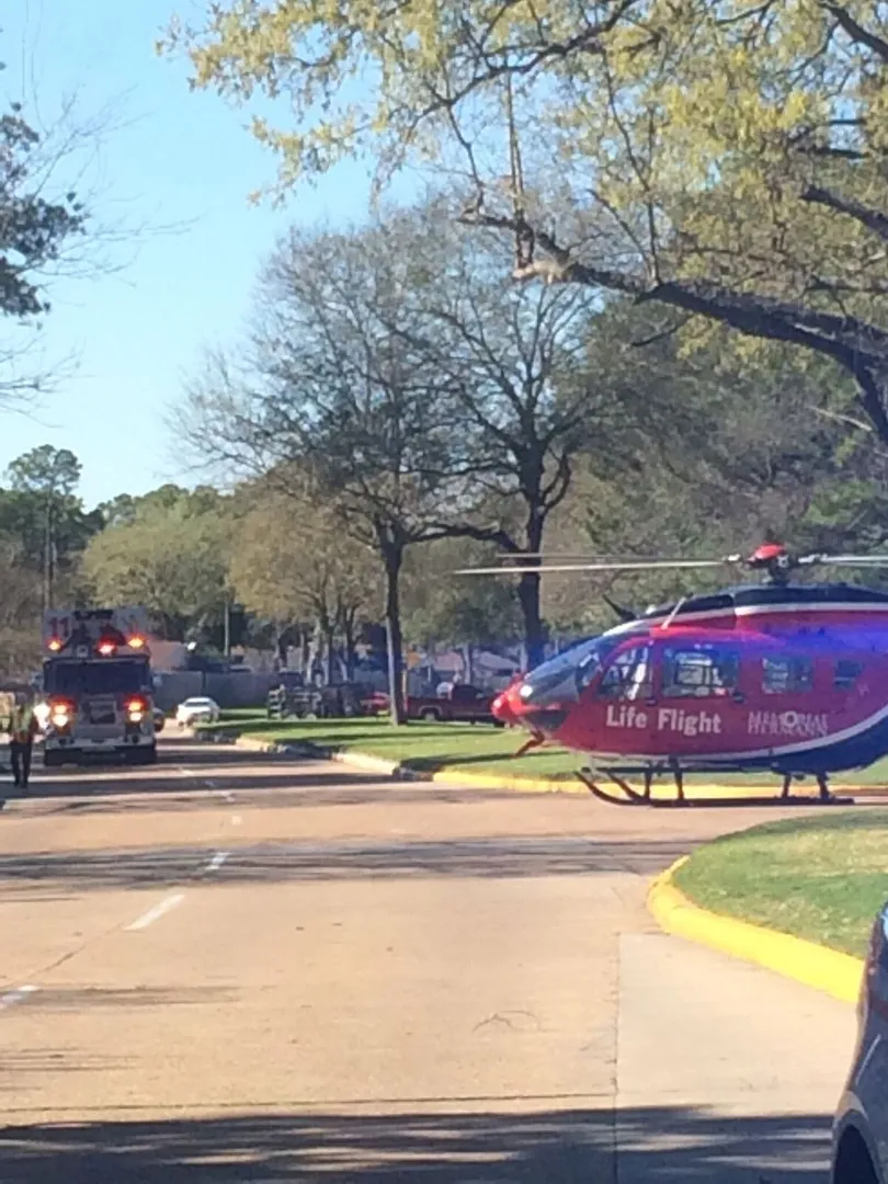 A Life Flight helicopter is landed on a suburban street, with emergency vehicles in the background.