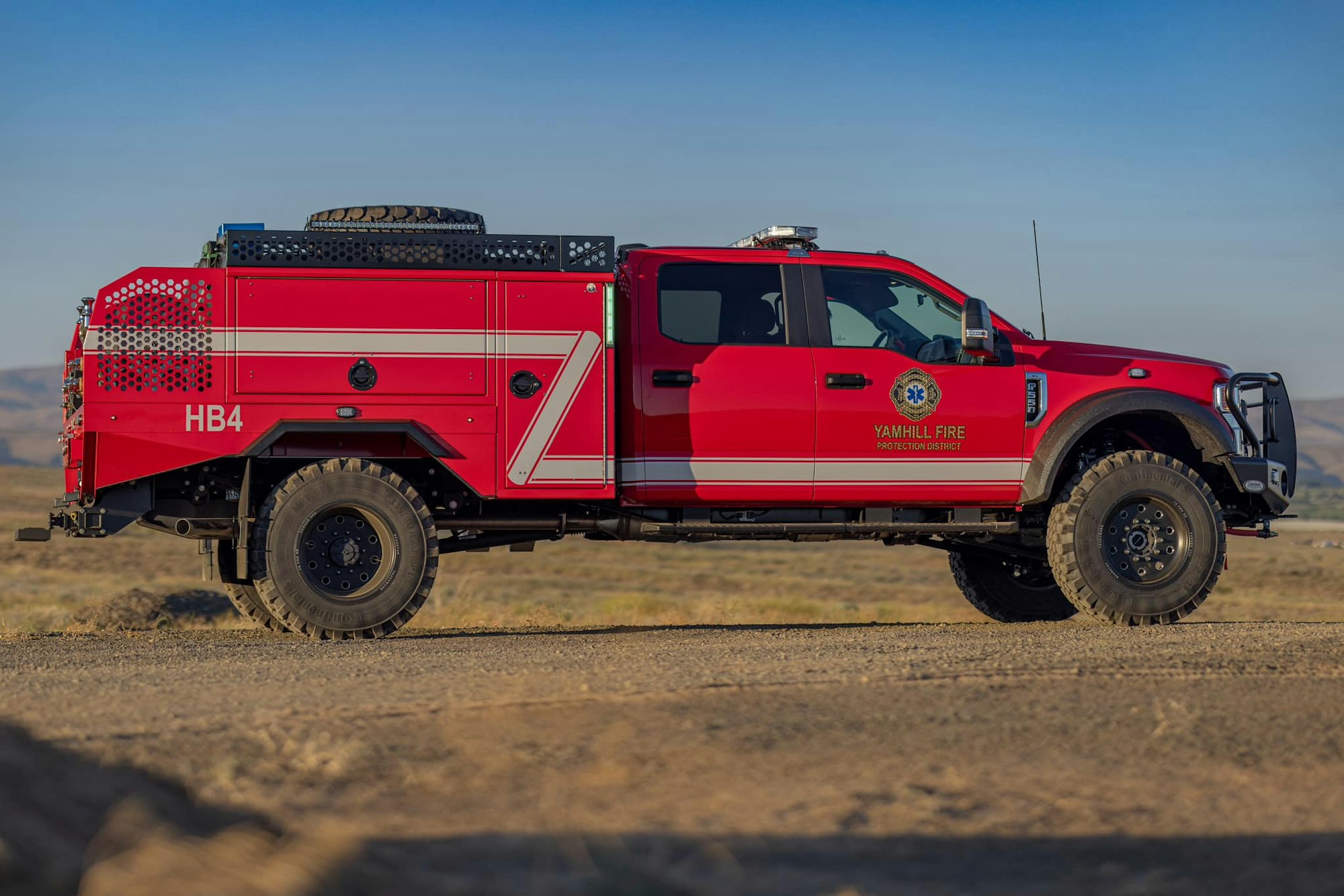 Red fire truck labeled "Yamhill Fire Protection District" on a dirt road.