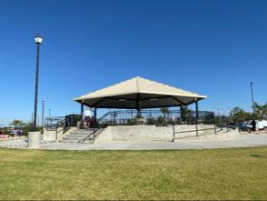 The image shows a gazebo in a park with a clear blue sky and green grass around it.