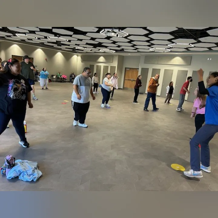 A diverse group of people are participating in an exercise class in a spacious indoor setting.