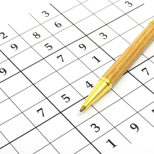 A sudoku grid with a pen placed on it, ready for solving puzzles.