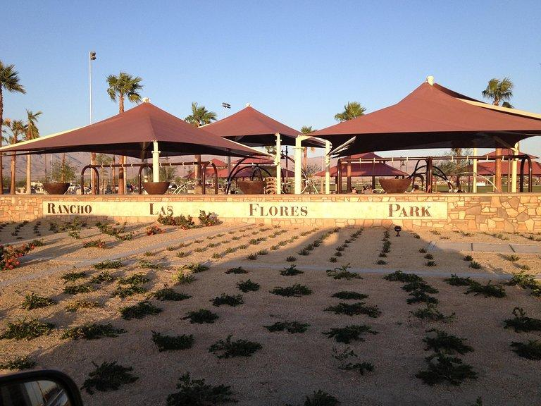 Rancho Las Flores Park features shaded areas, palm trees, and a gravel landscape, creating a tranquil outdoor space.