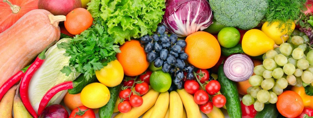 A vibrant assortment of fresh fruits and vegetables, including greens, oranges, bananas, grapes, and peppers.