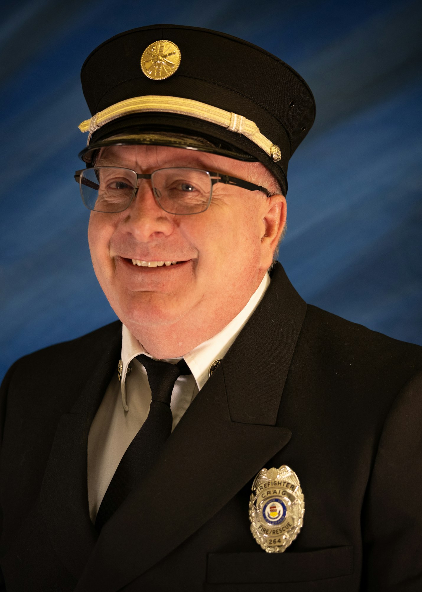 The image shows a smiling person in a uniform with a hat and badge, set against a blue background.