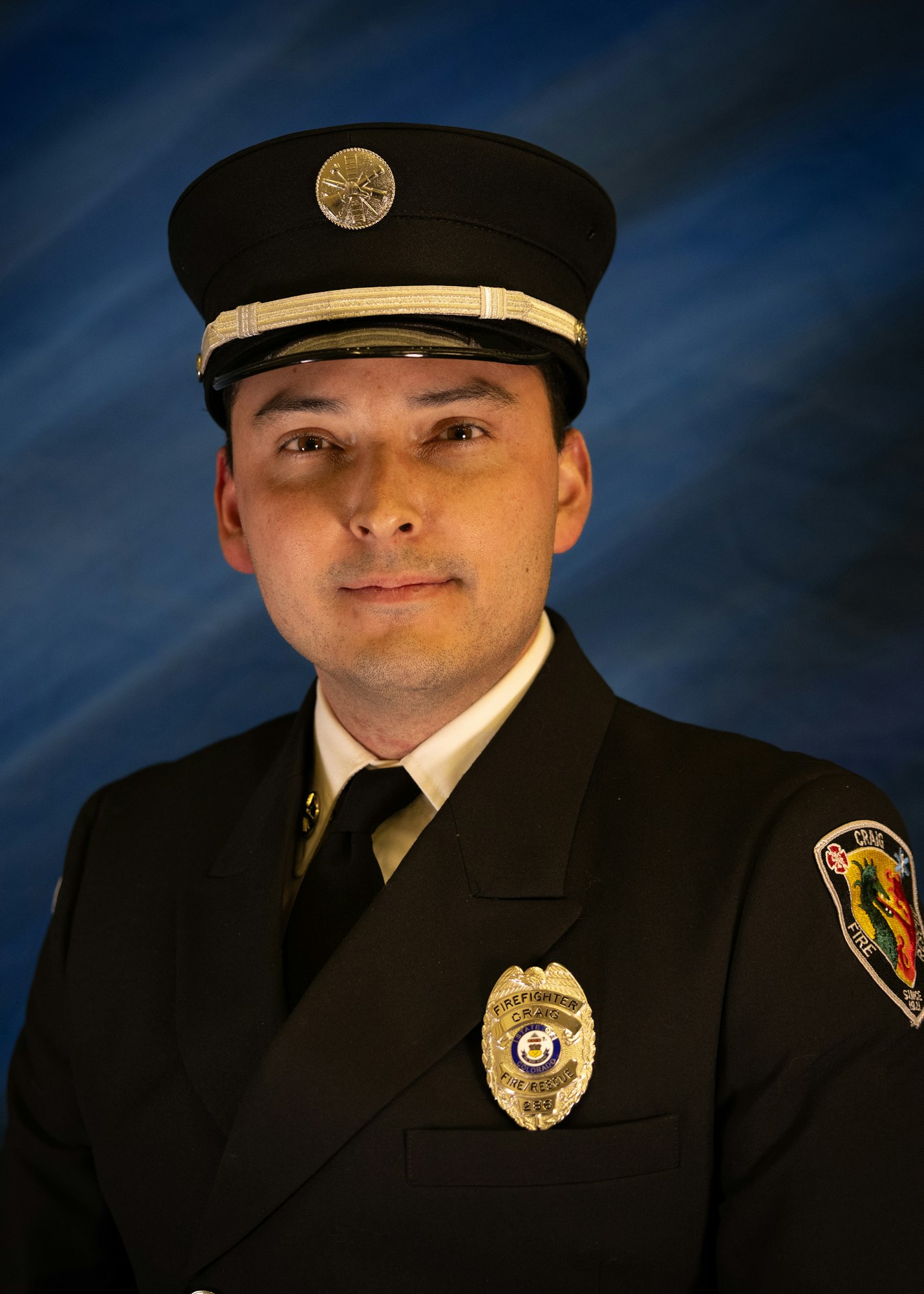The image features a uniformed firefighter or rescue officer posing against a blue backdrop, showcasing their badge and hat.
