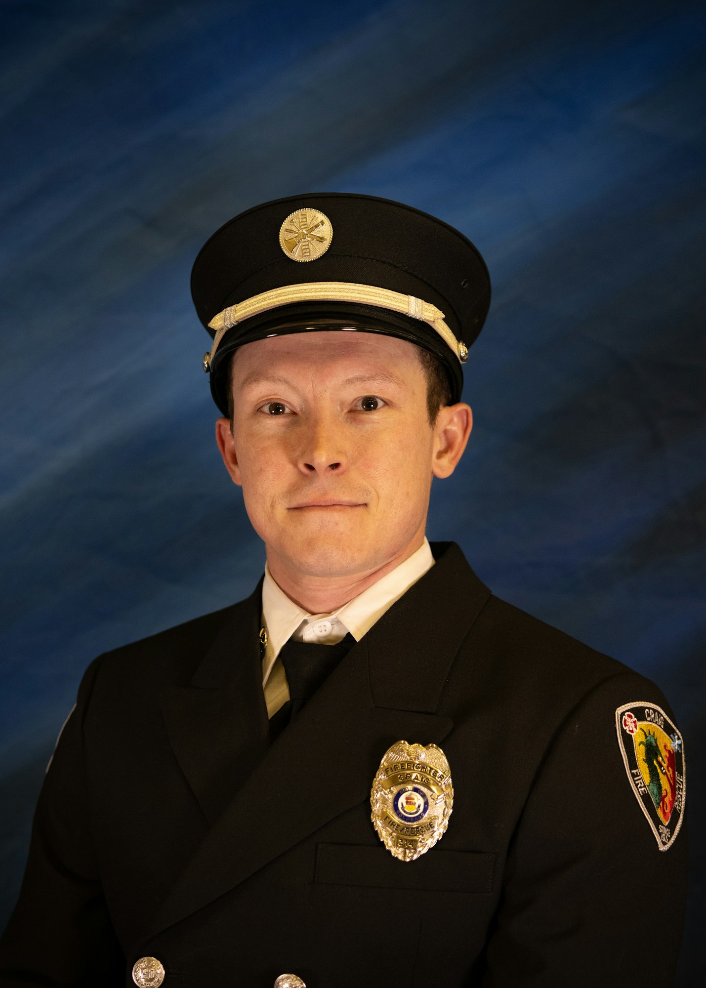 The image features a person in a formal firefighter uniform with a cap, posing against a blue background.