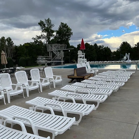 a line of lounge chairs outside by a pool