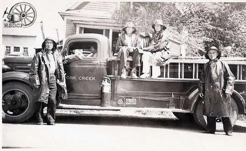 Historical photograph of firefighters posing with their fire enging