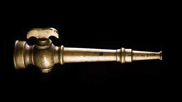 The image shows a vintage brass tap or nozzle, likely used for dispensing liquid.