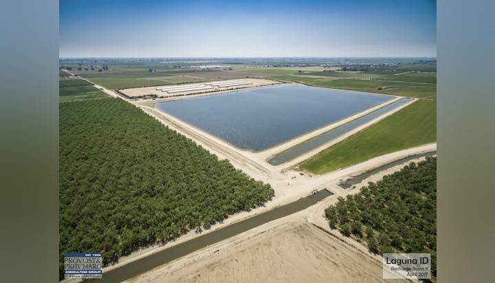 An aerial view of a water recharge basin surrounded by farmland and orchards.