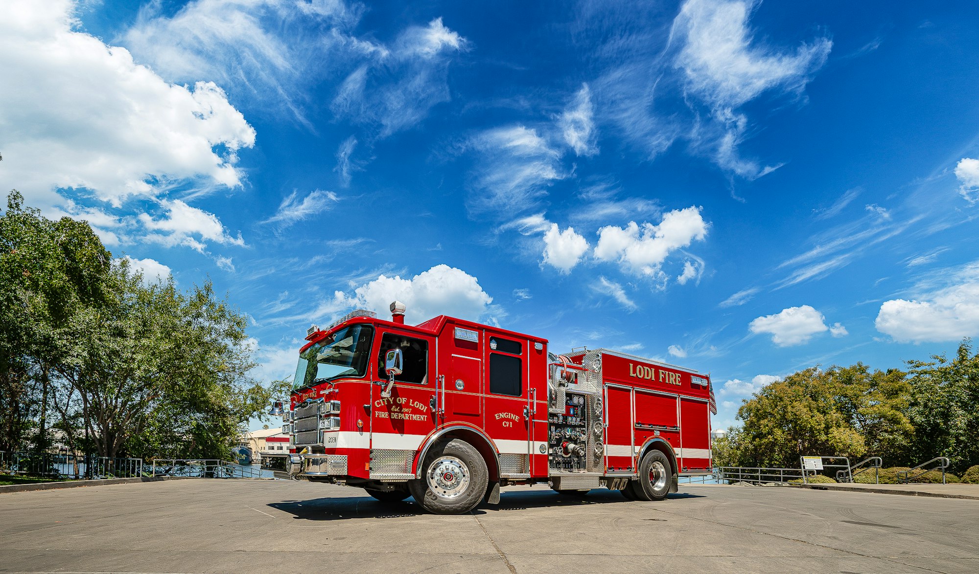 A vibrant red fire truck parked outdoors under a clear, sunny sky.