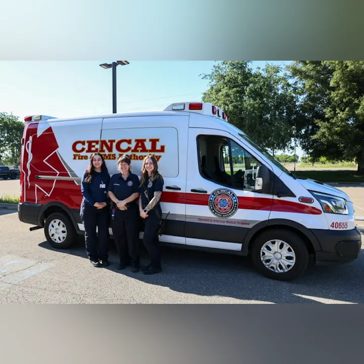 Three women stand together in front of a CENCAL Fire EMS Authority vehicle in a sunny, outdoor setting.