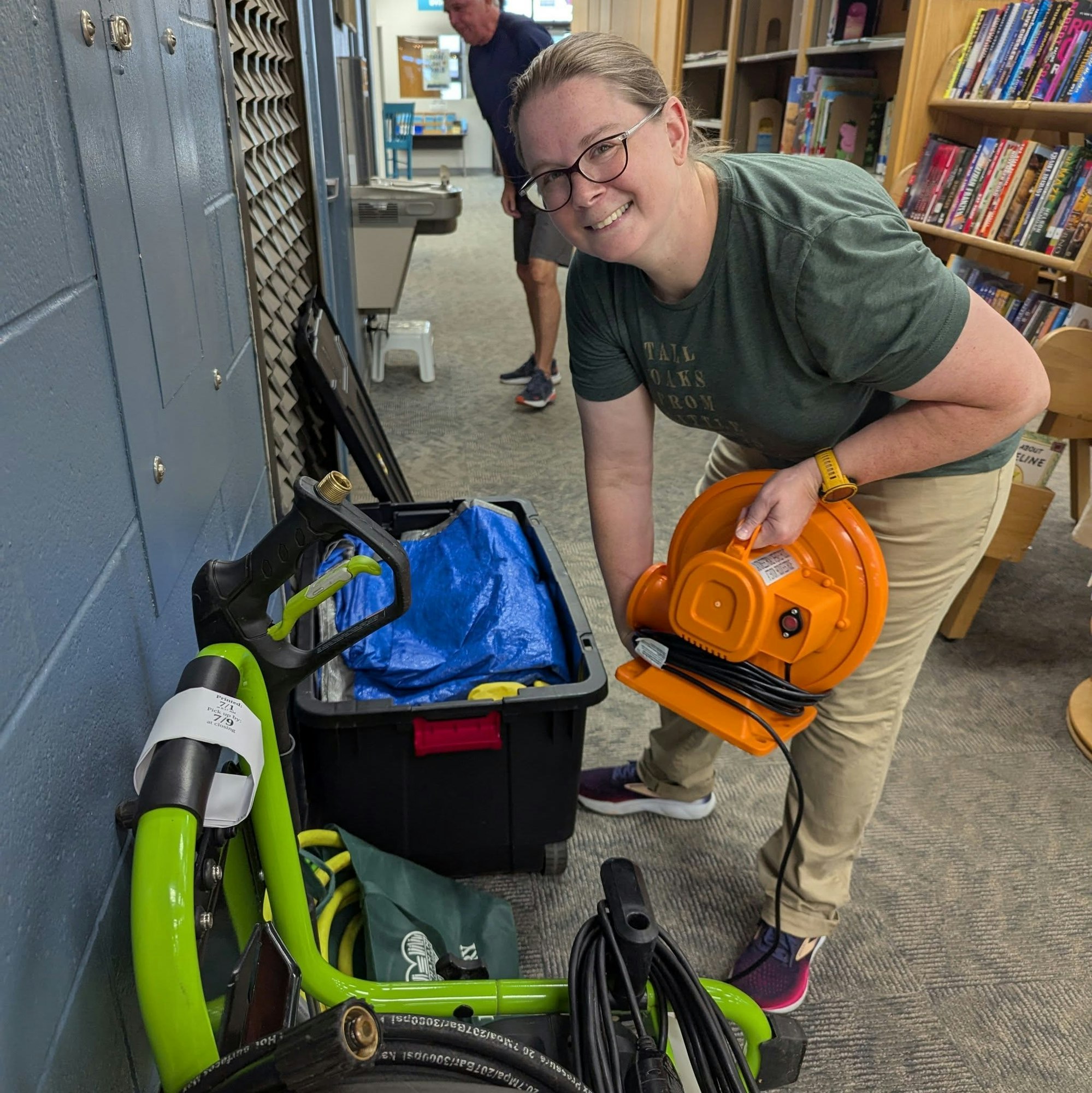 A person is organizing equipment, including a power cord and tools, in a library or community space.