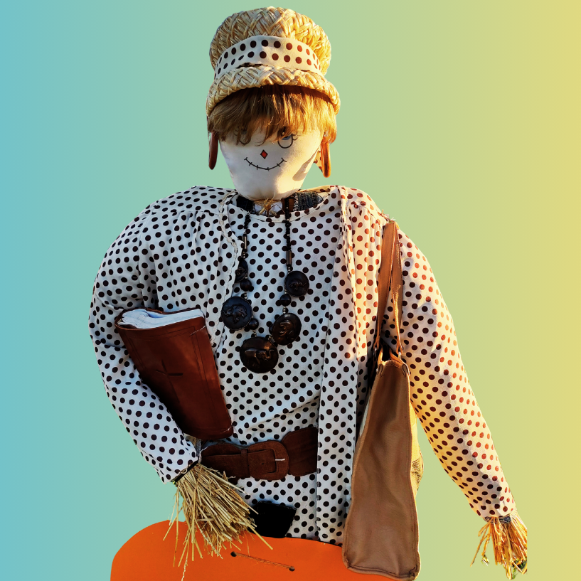 A scarecrow with a polka dot shirt, straw hat, beaded necklace, and bag, holding a book against a gradient background.
