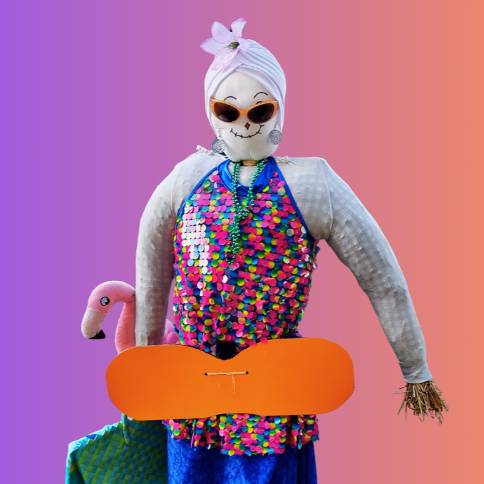 A colorful scarecrow-like figure wearing sunglasses, sequins, and a hat, next to a pink flamingo against a pink and purple gradient background.
