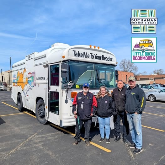 Four people standing in front of the Little Bucks Bookmobile .