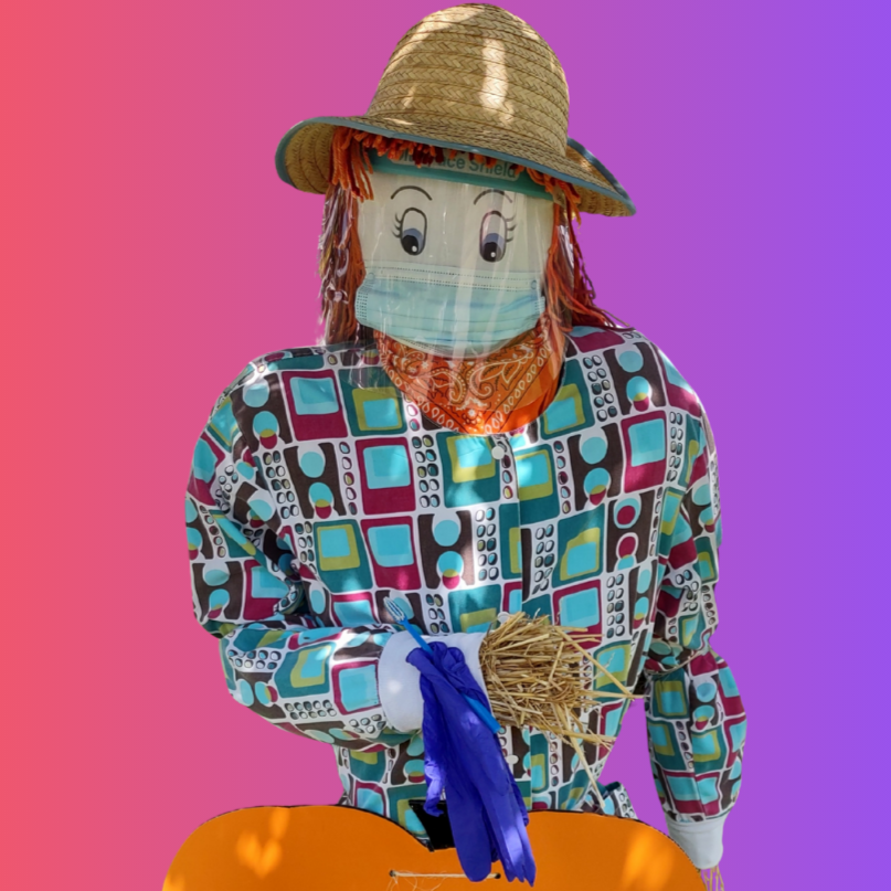 A scarecrow with a colorful shirt, straw hat, face shield, and mask holding straw against a pink and purple background.