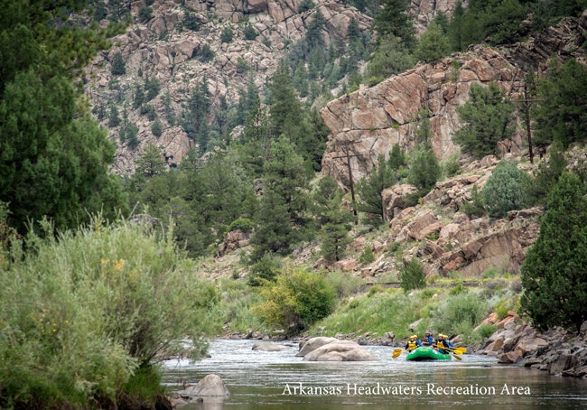 Rafters navigate a river through a rocky landscape at Arkansas Headwaters Recreation Area.