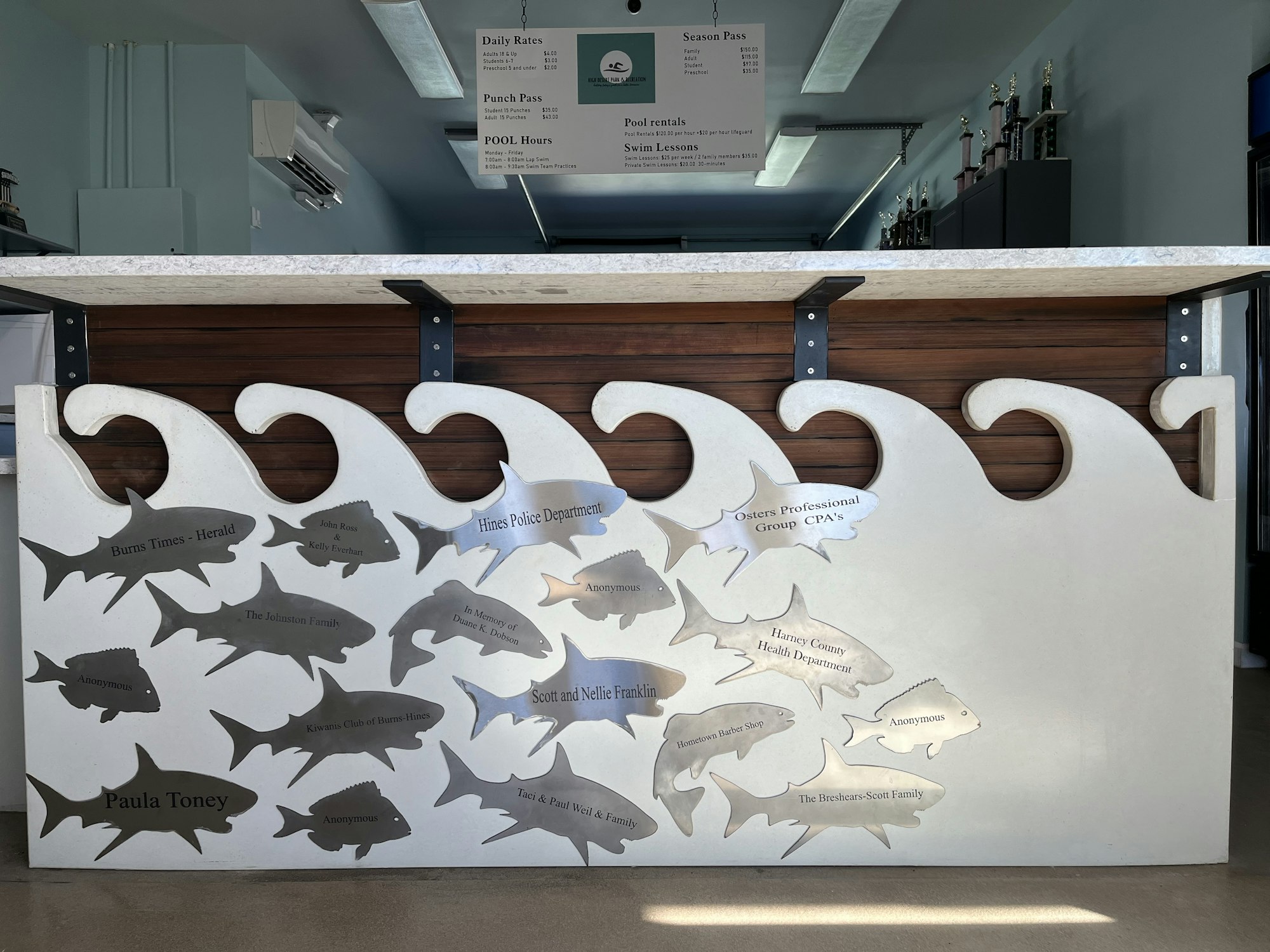 Countertop with a fish-shaped metal donor recognition board featuring names and organizations.