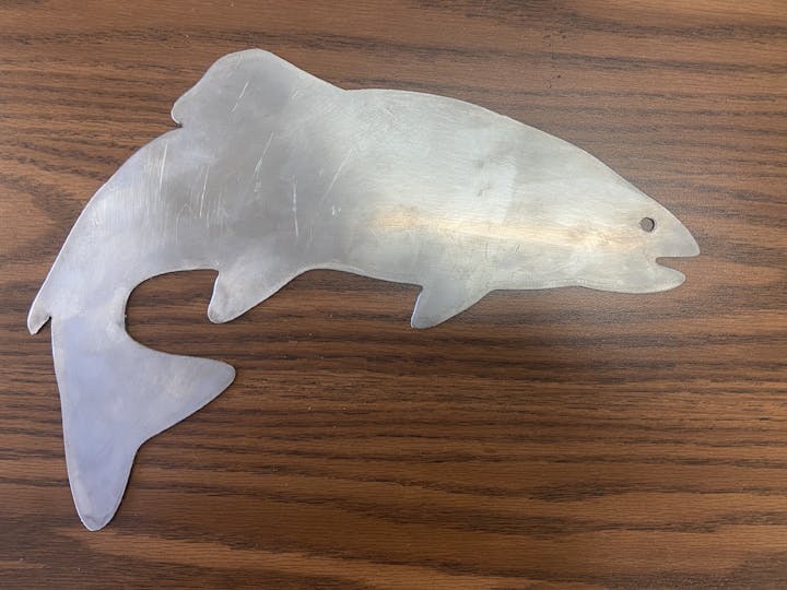 A metal fish-shaped cutout on a wooden surface.