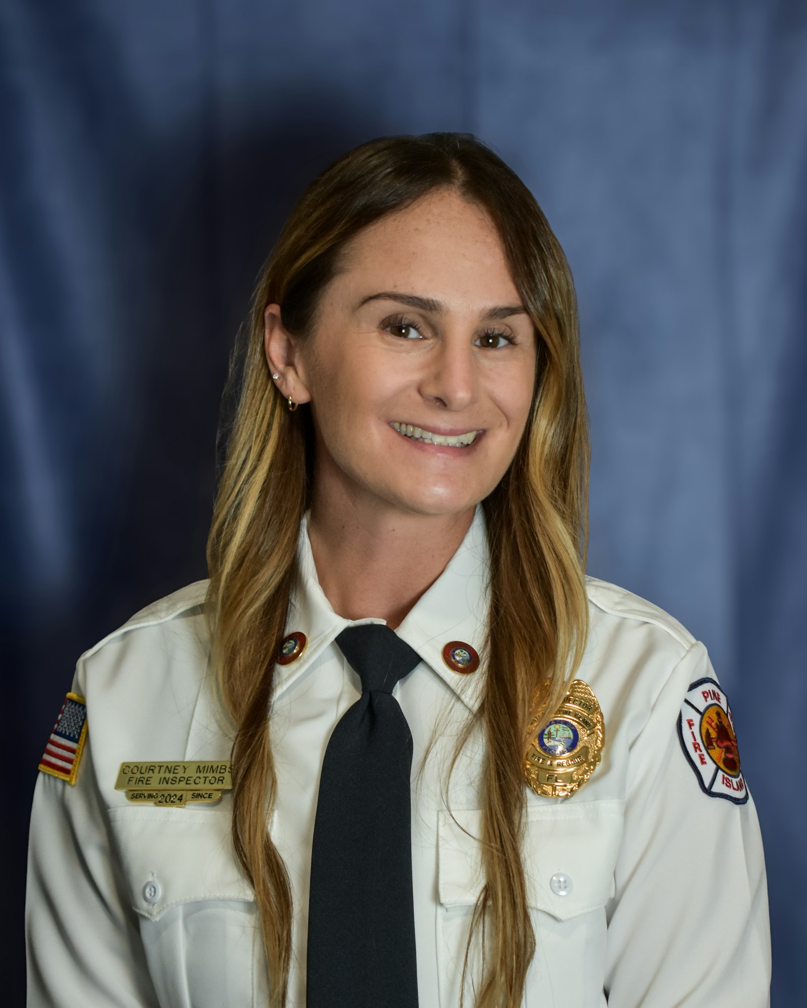 A person in uniform with a badge and insignia on a blue background.