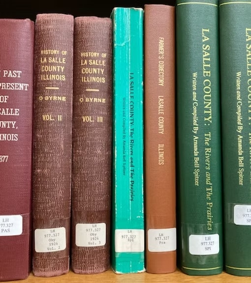 Books about La Salle County, Illinois, including histories and directories, are lined on a shelf.
