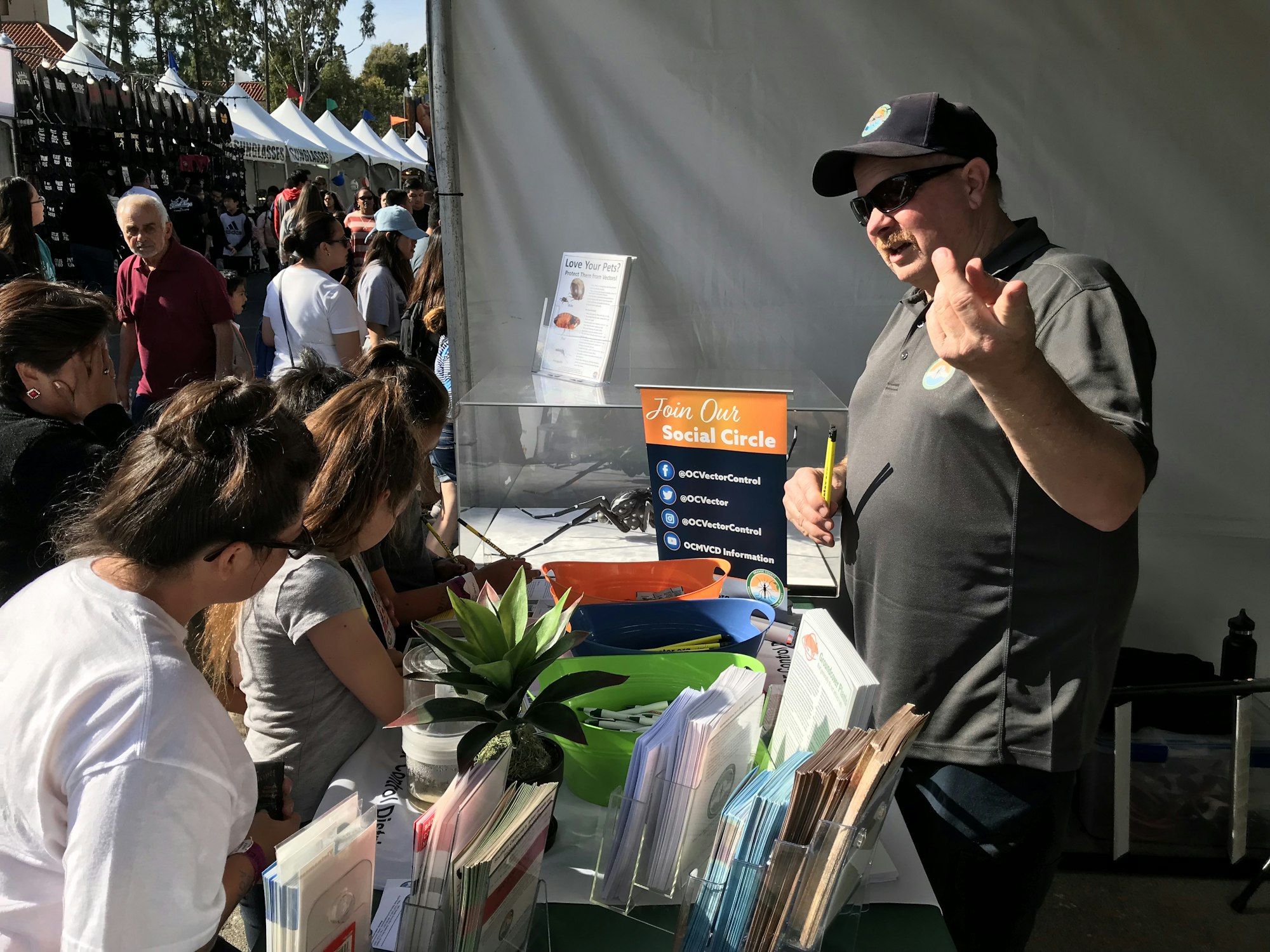 May contain: hat, clothing, person, man, adult, male, poster, advertisement, baseball cap, cap, woman, female, plant, glasses, accessories, handbag, bag, finger, hand, and body part