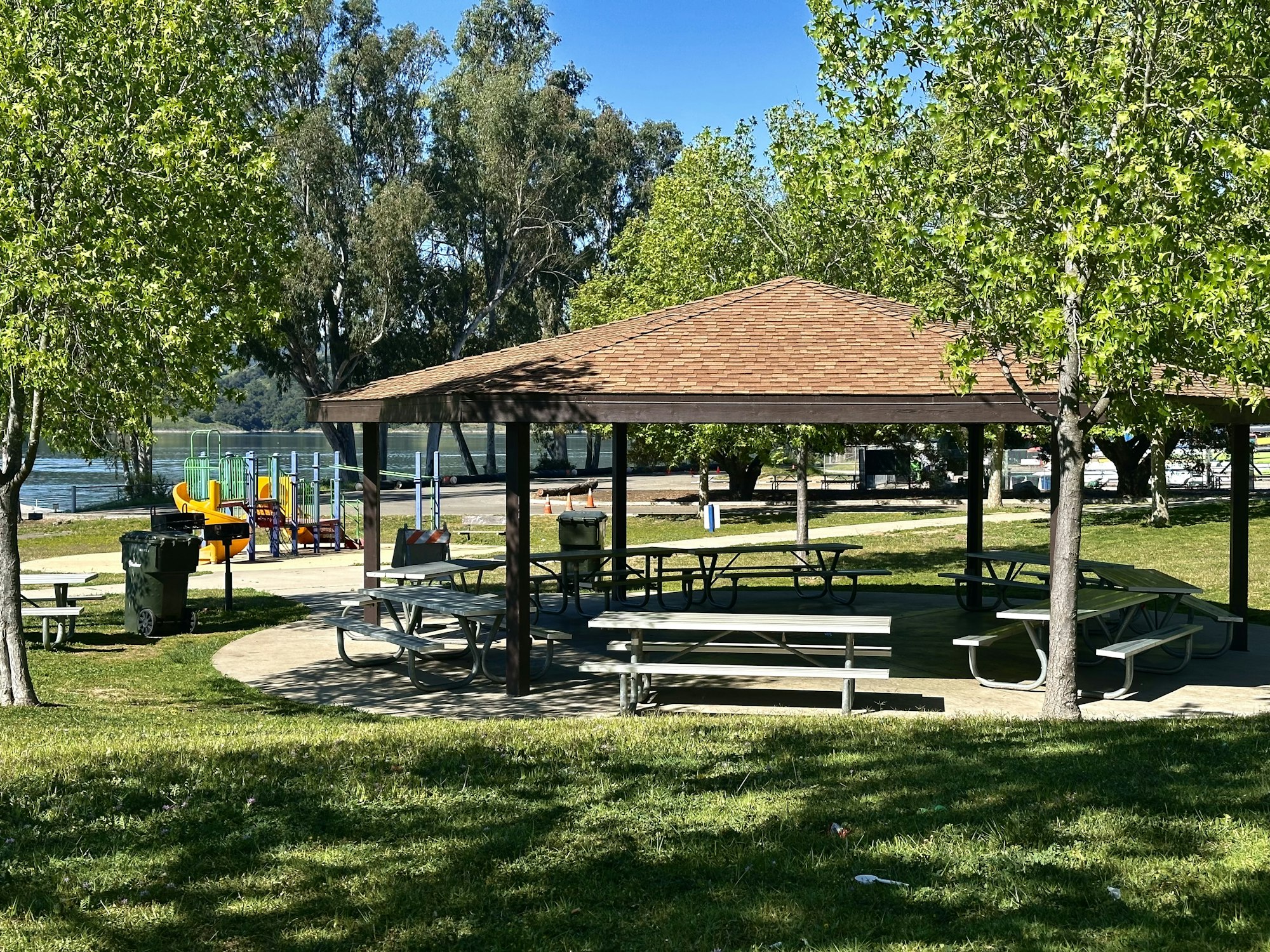A park with a gazebo, picnic tables, a playground, and trees.