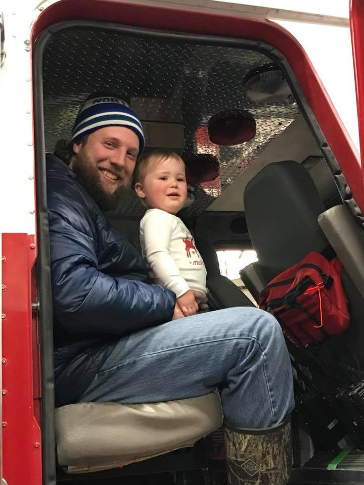 A man and a child sit together in the cab of a vehicle, smiling and enjoying each other's company.