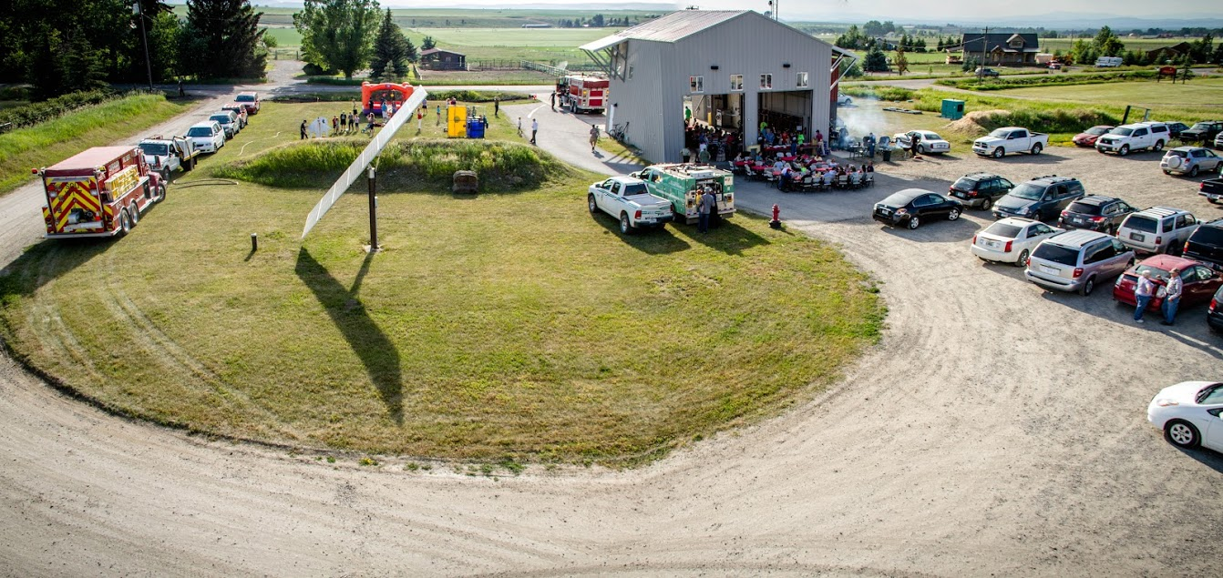A community event at a fire station featuring vehicles, a gathering, and activities outdoors.